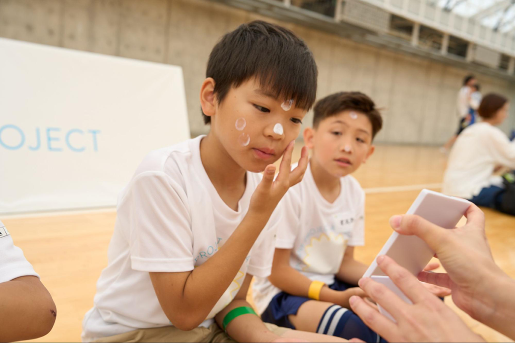 日焼け止めの塗り方を資生堂社員から学ぶ子どもたち