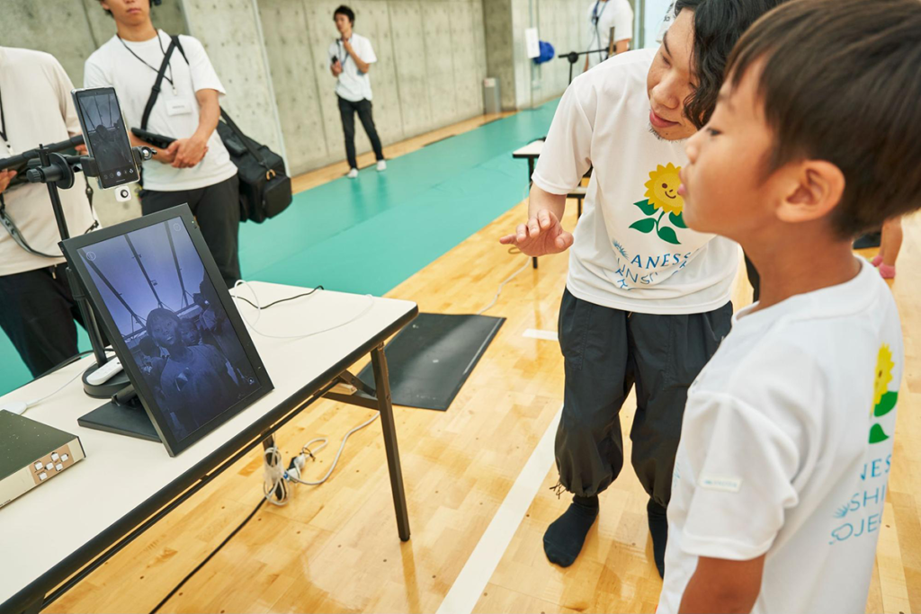 日焼け止めの塗り残しがないかUVカメラで確認する子どもたち