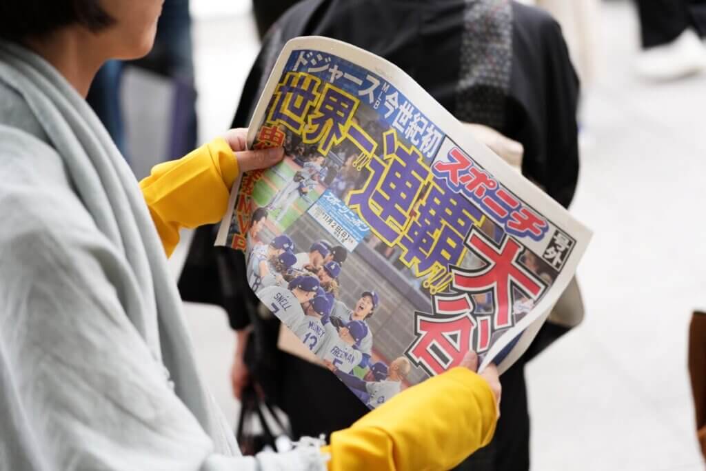 2025MLBワールドシリーズ第7戦を制し、ドジャース2連覇を伝える号外を手にする人=2025年11月2日、都内（写真：アフロ） 