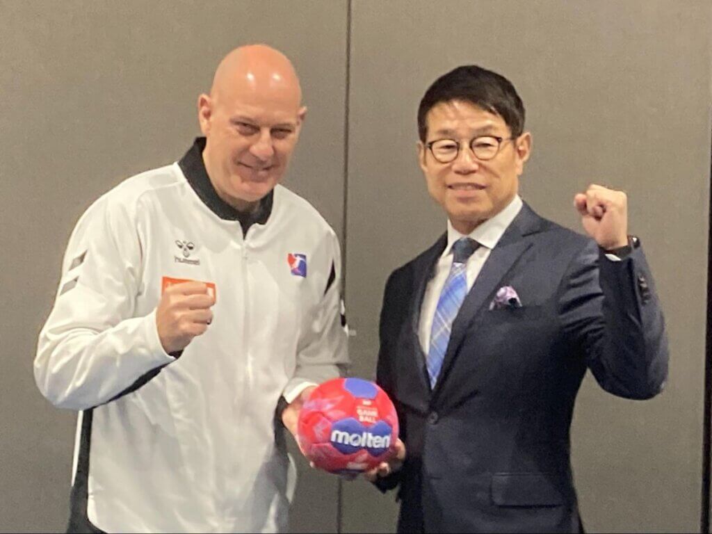 第27回IHF女子世界選手権メンバー発表会見でポーズをとるモーテン・ソウバク監督(左)と金丸恭文・日本ハンドボール協会会長=2025年11月8日、原田写す