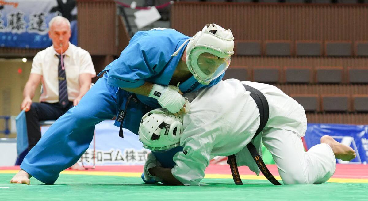 寝技になり、上から絞め技、関節技を狙う青の選手＝2025年11月のアジア選手権、大道塾提供