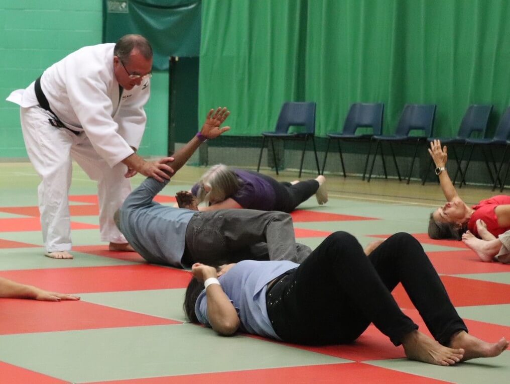 マットを敷いた床の上で、マイク・カラン教授（柔道着）から初歩のレッスンを受ける英国の高齢者たち＝カラン教授提供