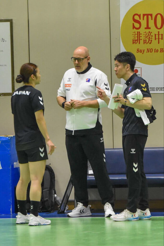 女子日本代表のモーテン・ソウバク監督（写真中央）と会話する秋山。外国人指導者とのちょっとしたコミュニケーションが、昔から得意だった＝2025年11月